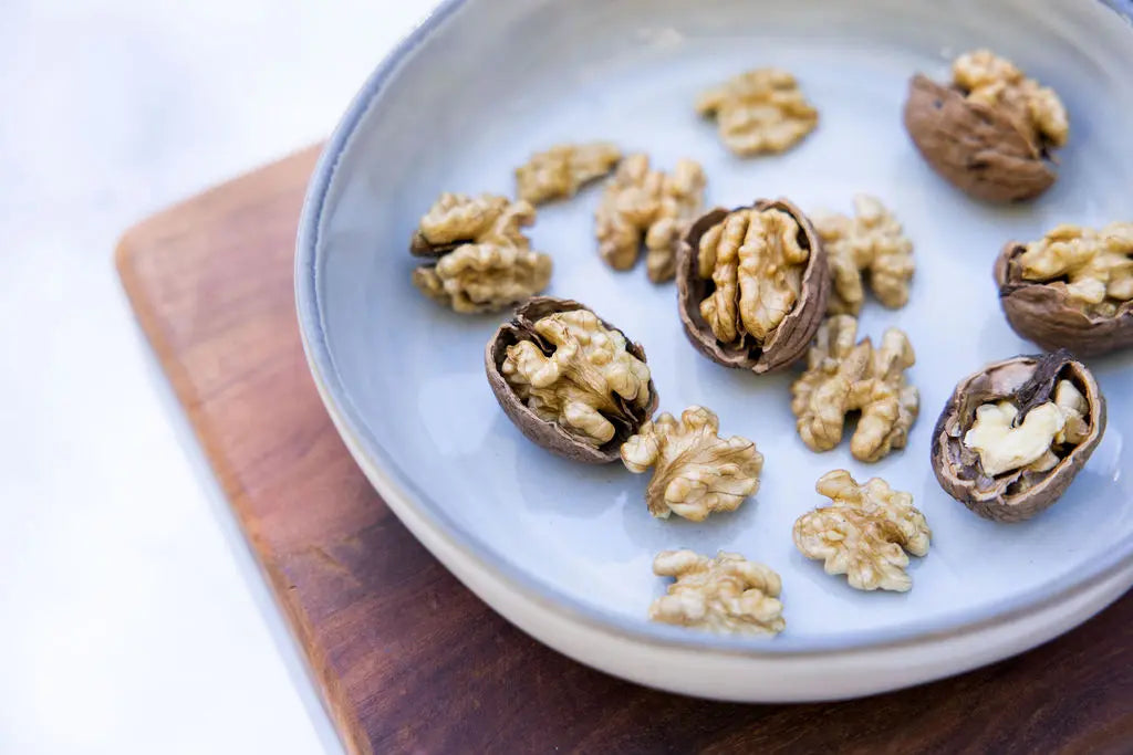 Shelled and unshelled walnuts on a plate.